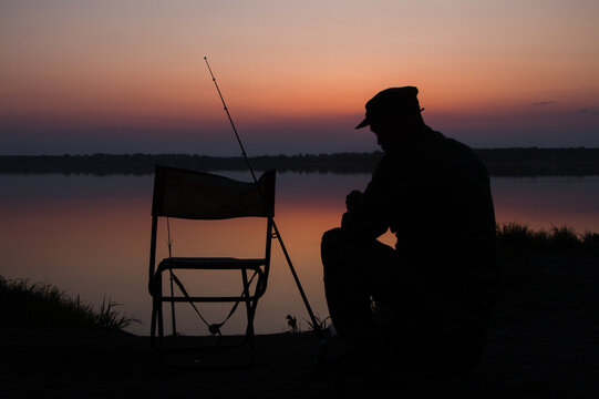 A fisherman silhouette fishing at sunset. Freshwater fishing, catch of fish. High quality photo