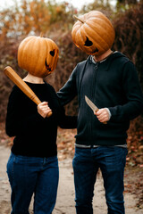A girl with a pumpkin on her head looks at a guy with a pumpkin on her head