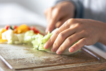 A woman cuts vegetables on a cutting board.