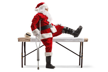 Profile shot of Santa claus with a foot brace and crutch sitting on a medical bed