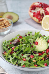 A plate with green rocket salad with pomegranate and avocado