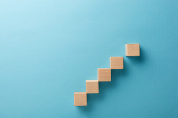 wooden cubes in the form of a ladder with a hand on a blue background © Minakryn Ruslan 