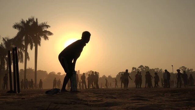 Silhouettes of young men playing cricket inside Ramna park at sunset, in Dhaka, sports in Bangladesh