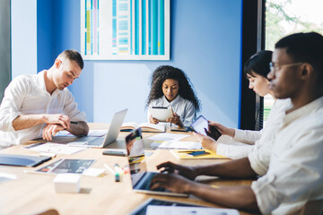 Obraz premium Concentrated multiracial coworkers using gadgets at meeting