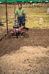 Farmer plows the land with a cultivator to prepare the soil for planting crops.