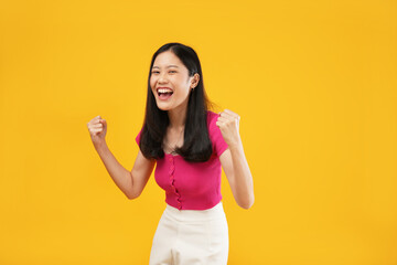Photo of a cheerful young Asian woman her hands clenched into fists and a happy smile, isolated on...