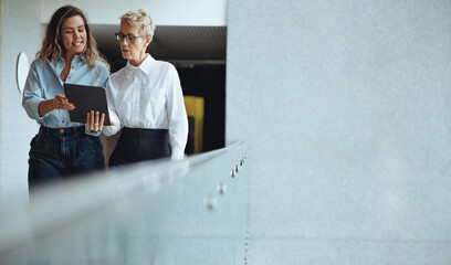 Mature business woman reading a financial report from her personal assistant in a modern office