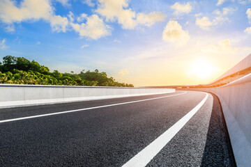 Highway road and green forest at sunset
