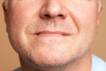 Obraz premium Close-up cropped photo of middle aged, 45s male face mouth, lips, bristle isolated beige studio background.