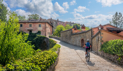 nice senior woman riding her electric mountain bike in a little village near Laterina in Val Darno, Tuscany, Italy 