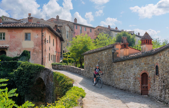 nice senior woman riding her electric mountain bike in a little village near Laterina in Val Darno, Tuscany, Italy
