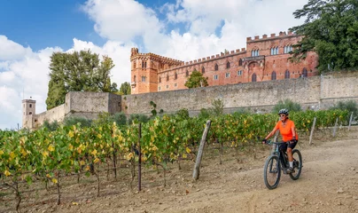 Fototapete Rund nice senior woman riding her electric mountain bike in the vineyards below Castello Brolio in the Ghianti Area of Tuscany,Italy  © Uwe