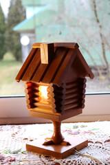 A wooden retro lamp in the form of a hut on chicken legs, a fairy-tale house with a burning window...