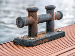 A small rusty mooring bollards on a yacht dock. Close-up.