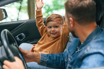 Father with his little son are sitting in the car