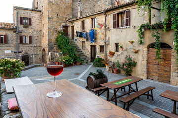 Bicchiere di vino su tavolo di un ristorante nel borgo medievale di Bolsena - obrazy, fototapety, plakaty