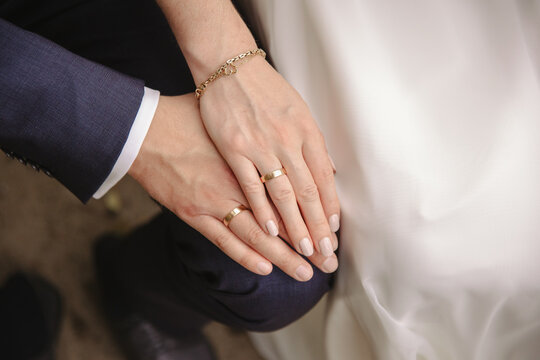 Hands of bride and groom with golden wedding rings 