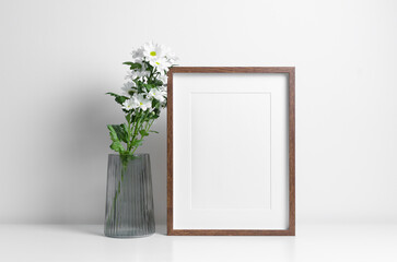 Blank picture frame mockup with white flowers bouquet in vase, vertical artwork frame mock up with...