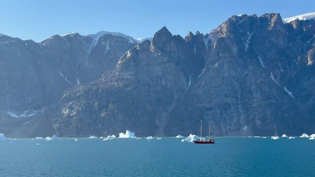 A two-masted yacht between icebergs in &Oslash; Fjord. Scoresbysund, Greenland.