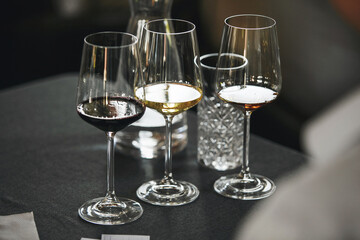 Elegant wine glasses with different white and red wines on the table during the preparation for the...