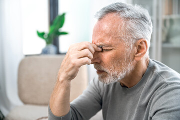 tired mature man suffering from headache at home