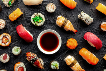 Sushi with soy sauce. An assortment of rolls, maki, nigiri etc, overhead flat lay shot on a black background. Japanese restaurant