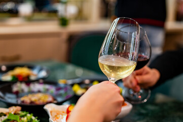 Close up of hands young couple man and woman clinking with glasses of red and white wine at restaurant