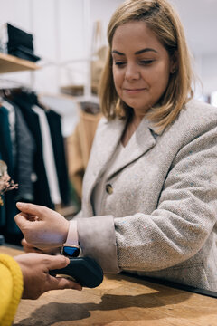 Boutique client processing contactless payment via smartwatch.