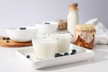 Obraz na płótnie Canvas Bowls with yogurt, berries, bottle with milk and jars on white background