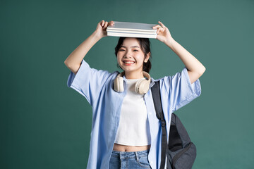 Fototapeta na wymiar Portrait of a beautiful Asian student on a green background