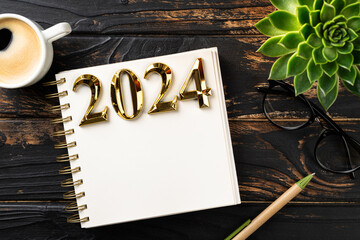 New year resolutions 2024 on desk. 2024 goals list with notebook, coffee cup, plant on wooden table. Resolutions, plan, goals, action, idea concept. New Year 2024 resolutions. Copy space