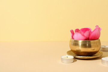 Flower in copper bowl and candles on light background, space for text