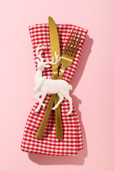 Cutlery and decoration on towel on pink background, top view