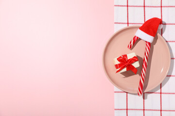 Gift box and Christmas candy cane on plate on pink background, space for text - obrazy, fototapety, plakaty