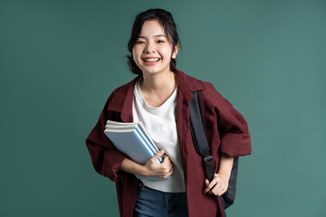 Portrait of a beautiful Asian student on a green background