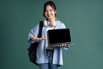 Fototapeta na wymiar Portrait of a beautiful Asian student on a green background