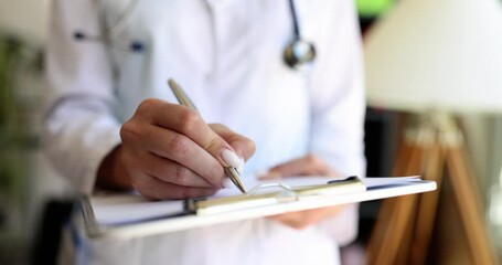 The woman writes a doctor with a pen on the folder, close-up. Patient medical data, ambulance reception