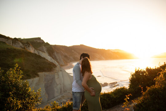 Anonymous pregnant couple hugging in nature