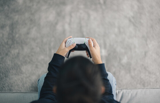 Crop woman playing videogame with controller at home