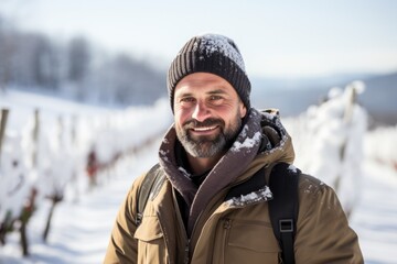 Fototapeta na wymiar Portrait of an ice wine maker in snow-covered vineyard background with empty space for text 