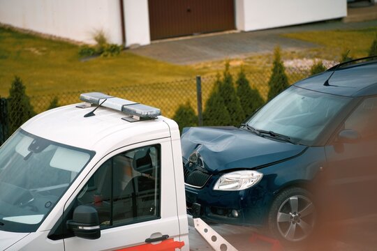 Tow truck with broken car on country road. Tow truck transporting car on the highway. Car service transportation concept.