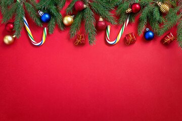 Holiday Christmas and New Year red background with candy canes, fir tree branches and xmas balls.
