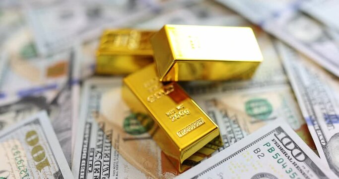 Gold ingots against a background of money, close-up, slowmotion. Concept of investment in gold, bank exchange
