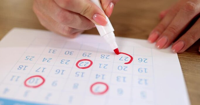 A woman draws red numbers on the calendar, close-up, shallow focus. Concept agenda, important date
