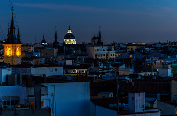 View of the rooftops of Madrid at dusk, with illuminated monuments