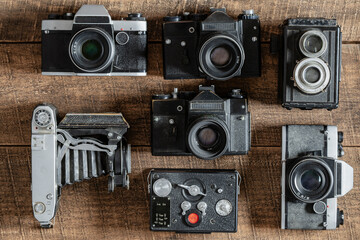 Set of vintage film camera from the times of the USSR on a wooden background, closeup, top view. Line of old retro cameras