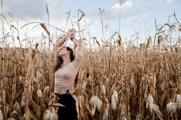 Dried corn, harvest. Girl in dry corn. Autumn aesthetics. The girl reaches out to the sky from the...