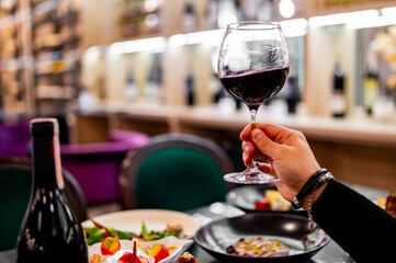 man hand holding a glass with red wine in a restaurant