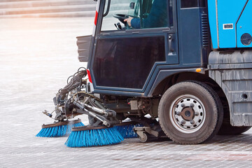 Compact washing machine clean city street, municipal sweeper. Compact vacuum sweeper washing paving slabs from rock salt. Road sweeper vehicle brushing sidewalk.