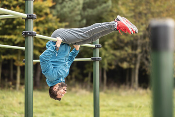 Young man working out calisthenics in an outdoor gym using parallel bars. A good looking athlete is...